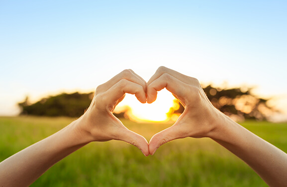 Hands making a heart image in front of a beautiful landscape