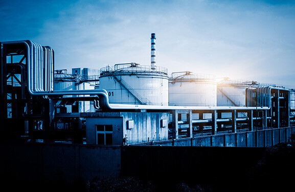 Industrieanlage mit Silos und Rohrleitungen im Schein der aufgehenden Sonne