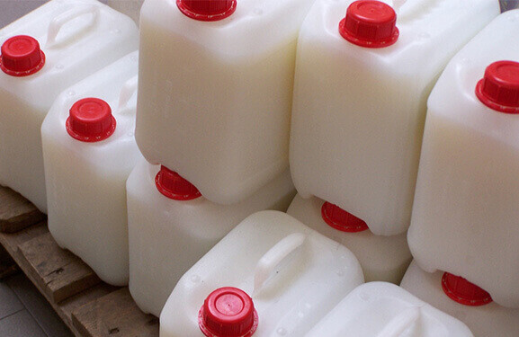 Stacked white canisters with red screw top on a wooden pallet 