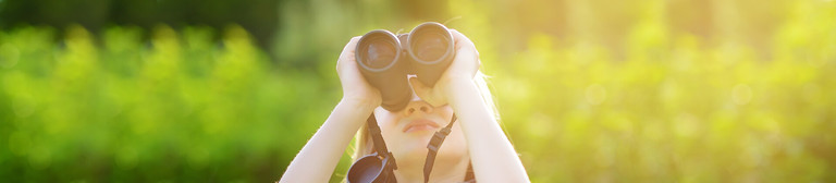 A child holding binoculars looks at nature