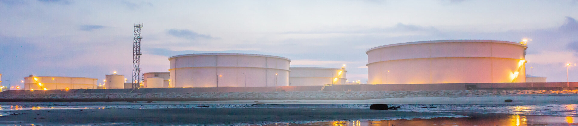 Una planta industrial iluminada a orillas del mar durante el amanecer